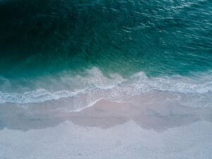 Stunning aerial shot of turquoise ocean waves washing onto a pristine sandy beach, perfect for backgrounds.